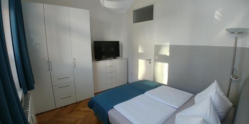 een kleine witte slaapkamer met een bed en een televisie bij attraktives 2-Zimmer-Apartment im Stadtzentrum in Rudolstadt