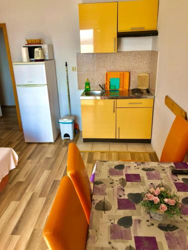 a kitchen with a table and a kitchen with yellow cabinets at Apartments Anita and Zoran in Stanići