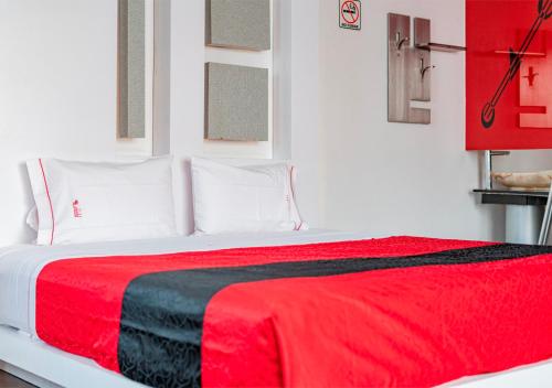 a bedroom with a red and black blanket on a bed at Hotel Puente Grande in Las Ánimas