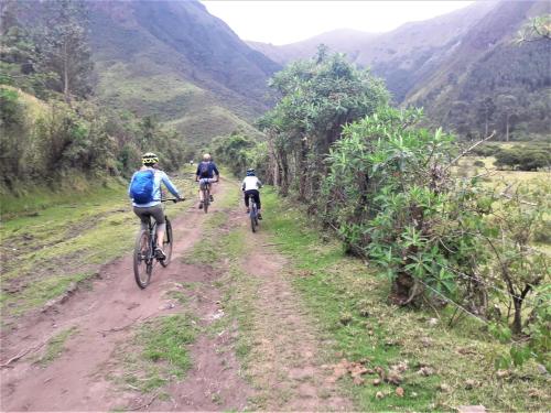 three people riding bikes down a dirt road at Green House Araque Inn in Otavalo