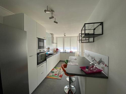 une cuisine avec des placards blancs et une table avec un ordinateur portable dans l'établissement Le Mun,3 étoiles-T2-60m2-balcon-parking-wifi-linge-produits-face à la gerdarmerie-vue cathedrale, à Reims