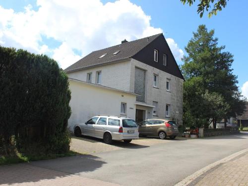 two cars parked in front of a large house at Apartment in the Teutoburg Forest in Blomberg