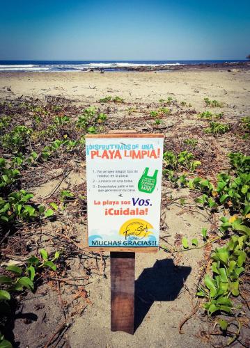 a sign in the sand on a beach at Tapas & Surf in Petacaltepe
