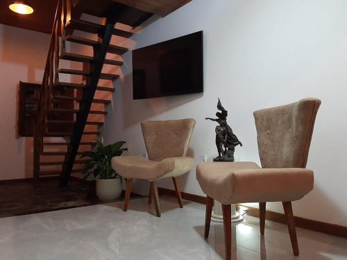uma sala de estar com duas cadeiras e uma televisão em Loft Colibri Mucugê em Mucugê