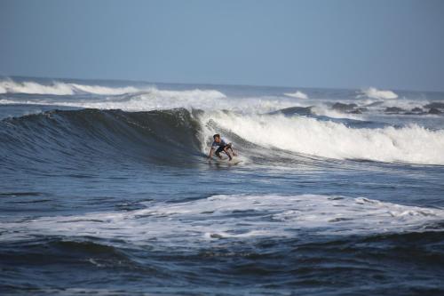 a person riding a wave on a surfboard in the ocean at Tapas & Surf in Petacaltepe