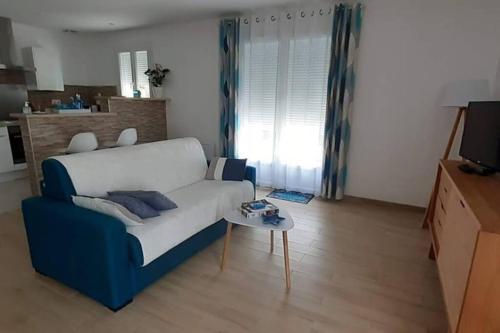 a living room with a blue and white couch and a table at Le logis de Chantal en pays royannais in Arvert