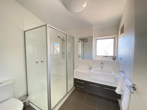 a white bathroom with a shower and a sink at Humffray 3 in Dinner Plain