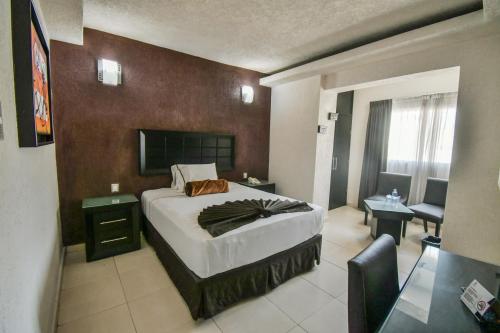 a bedroom with a bed and a desk and a chair at Hotel Portonovo Plaza Centro in Guadalajara