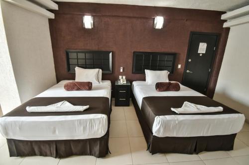 a hotel room with two beds with white sheets at Hotel Portonovo Plaza Guadalajara in Guadalajara