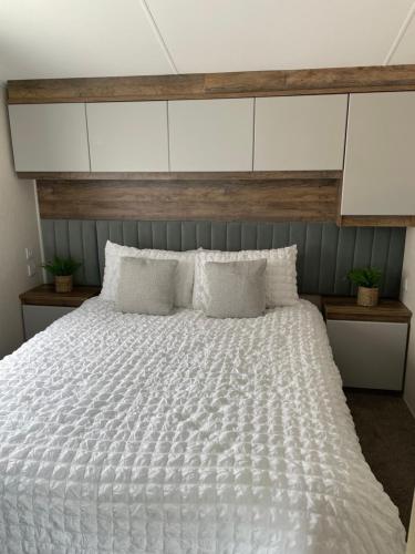 a bedroom with a large white bed with a wooden headboard at Lazy Bear Lodge Northumberland in Swarland