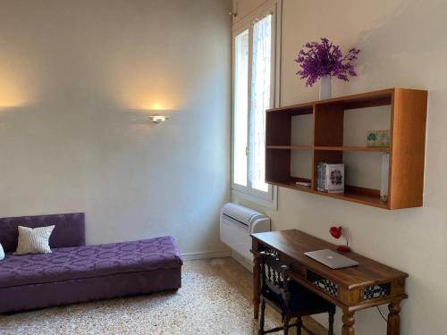 a living room with a desk and a purple couch at CA FOSCARINI 1 in Venice