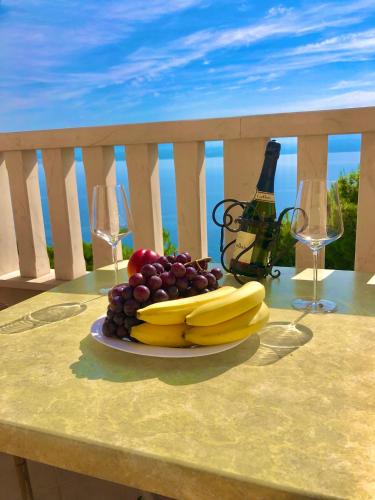 a plate of fruit on a table with wine glasses at Apartments Anita and Zoran in Stanići