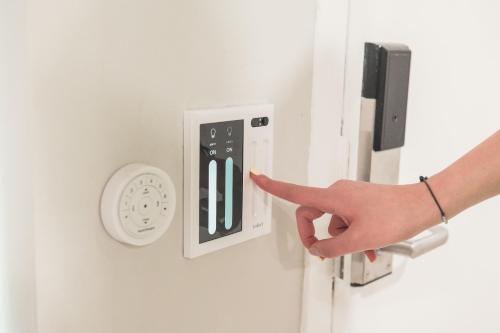 a person pointing at a light switch with their finger at Omeo Suites in Alhambra