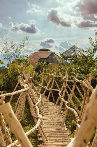 a wooden bridge over a field with a building in the background at Nacimiento Glamping in San Agustín