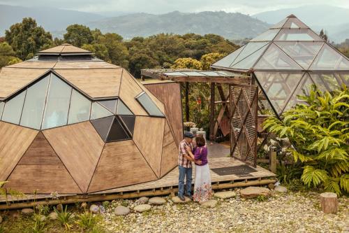 a couple standing in front of a wooden house at Nacimiento Glamping in San Agustín