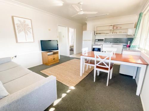 a kitchen and living room with a table and a couch at Pacific Sun Bargara in Bargara