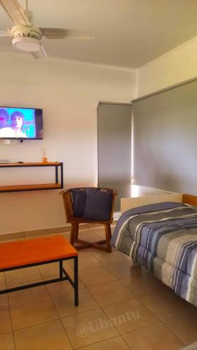 a bedroom with a bed and a tv on the wall at UBUNTU in Concepción del Uruguay