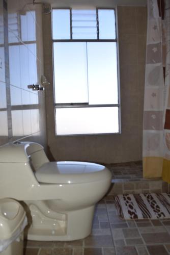 a bathroom with a toilet and a window at Marlon's House Puno-Peru in Puno