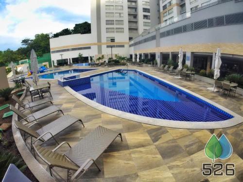 a swimming pool with chairs and a building at Park Veredas - Apto 526 - Flat Service in Rio Quente
