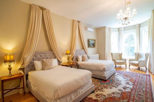a bedroom with two beds and a chandelier at Queen Anne Inn in Annapolis Royal