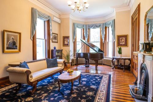 a living room with a couch and a piano at Queen Anne Inn in Annapolis Royal