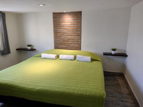 a bedroom with a green bed with two pillows at Mi Depa Vainilla en pleno Centro de la Ciudad in Ciudad Valles