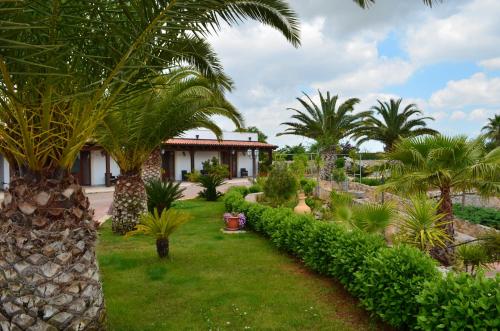 un jardin avec des palmiers et une maison dans l'établissement Relais La Giara, à Mandurie