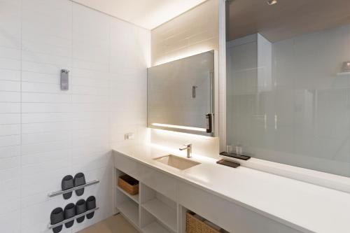 a white bathroom with a sink and a mirror at Grand City Hotel Changwon in Changwon