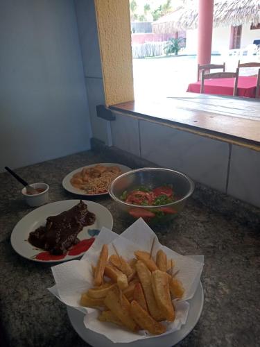 a table with two plates of food and french fries at Pousada Brasita in Cumbuco