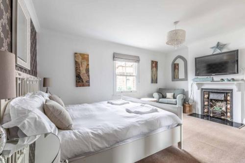 a white bedroom with a large bed and a fireplace at Windsor Town Centre Victorian townhouse sleeps 6 in Windsor