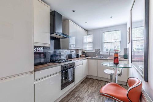 a kitchen with white cabinets and a glass table at Windsor Town Centre Victorian townhouse sleeps 6 in Windsor