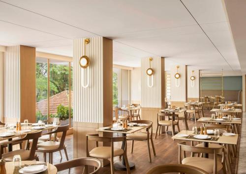 a restaurant with tables and chairs in a room at Vivanta Goa, Miramar in Panaji