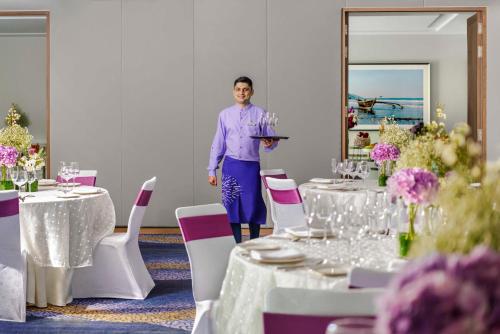 a man standing in a room with tables and chairs at Vivanta Goa, Miramar in Panaji