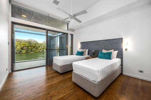 ヌーサヴィルにあるModern Riverview Escape with Private Poolのベッドが2つと大きな窓がある寝室