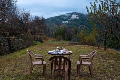 a table with two chairs and a table with a plate of food at StayVista at Sunshine Estate Serene 2BR Pet Friendly Villa in Chail with view in Chail