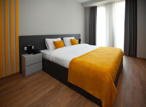 Old City Boutique Hotel في تبليسي: غرفة نوم بسرير كبير عليها بطانية صفراء