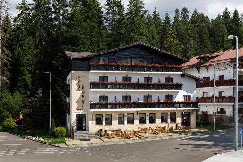 ein großes weißes Gebäude mit Tischen und Stühlen in der Unterkunft Manor Ski Hotel in Predeal
