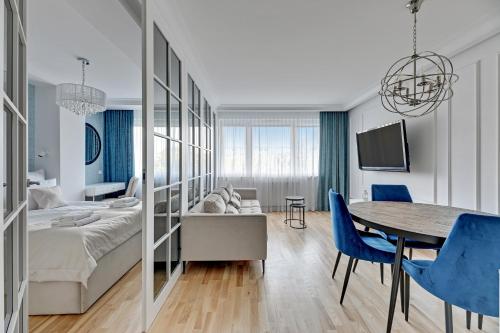 een woonkamer met een bed, een tafel en blauwe stoelen bij Downtown Apartments Seaside Primore in Gdańsk