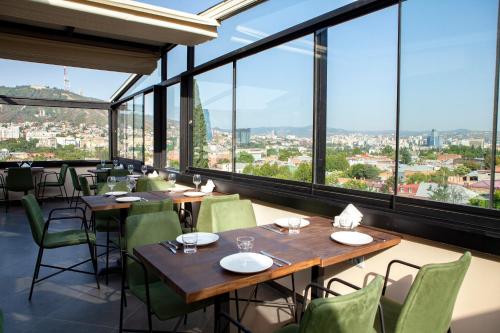 a restaurant with tables and chairs and large windows at Old City Boutique Hotel in Tbilisi City