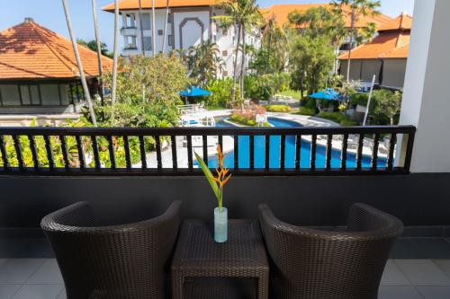 a table and chairs on a balcony with a view of a pool at Prime Plaza Suites Sanur – Bali in Sanur