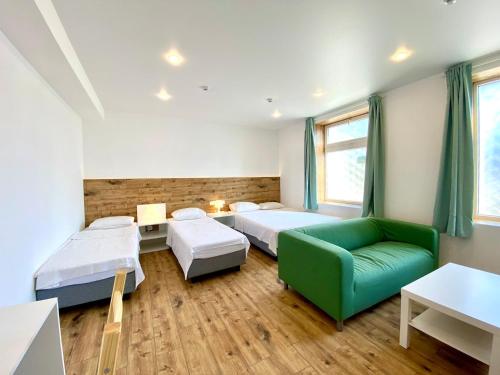 a room with two beds and a green couch at Barabulka Hotel in Sevastopol