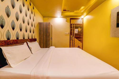 a bedroom with a large white bed with yellow walls at FabHotel GMC Grand in Lucknow