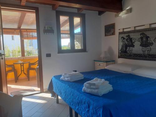 ein Schlafzimmer mit einem blauen Bett mit zwei Handtüchern darauf in der Unterkunft B&B Feronia in Posada