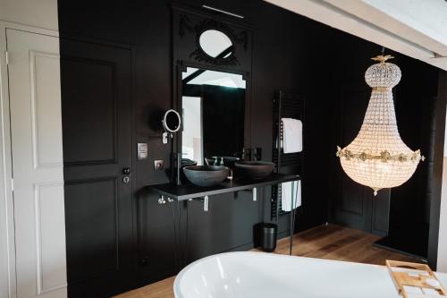 a black bathroom with two sinks and a tub at Maison Durieux in Limoges