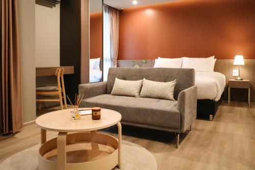 Habitación de hotel con sofá y cama en The Rise Suites Hotel, Chiang Mai - SHA Extra Plus, en Chiang Mai