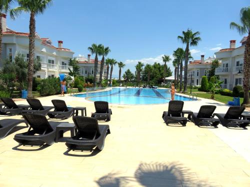 a group of lounge chairs and a swimming pool at TALYA TURİZM TATİLEVLERİ ve VİLLALARI in Belek