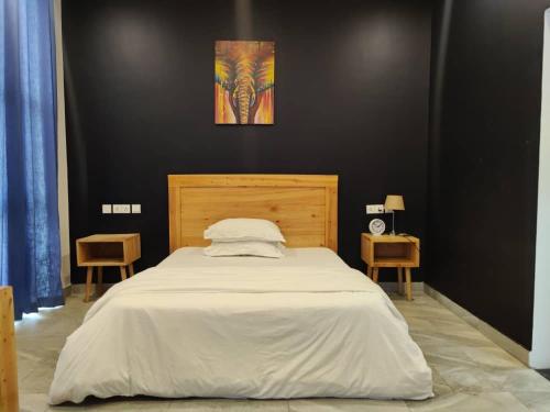 - une chambre avec un grand lit blanc et deux chaises dans l'établissement Tanzanite Apartment（Tanzanite Park）, à Dar es Salaam