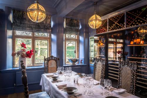 a dining room with a table and chairs and windows at Fischers Baslow Hall - Chatsworth in Baslow
