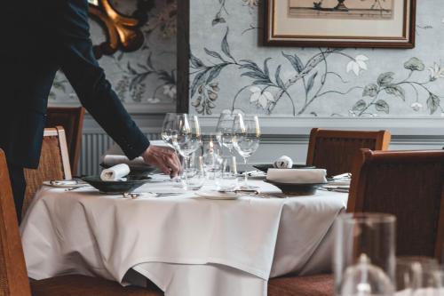 a person setting a table with wine glasses on it at Fischers Baslow Hall - Chatsworth in Baslow