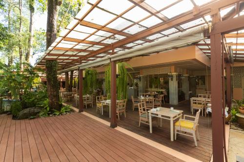 a patio with tables and chairs under a pergola at Khaolak Merlin Resort in Khao Lak